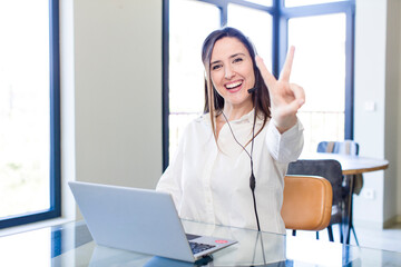 young pretty woman smiling and looking happy, gesturing victory or peace. telemarketer concept