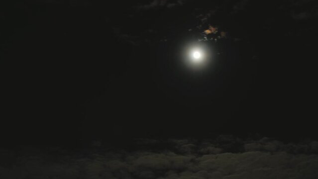 Full cold moon in the night sky. Clouds float past a glowing ball. Time-lapse shooting