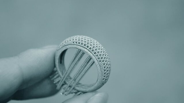 Object printed on 3D printer from metal powder by laser sintering. Woman holding metal ring in hand created on metal 3D printer. Selective laser melting technology. New modern technologies