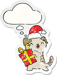 cute cartoon puppy with christmas present and hat and thought bubble as a distressed worn sticker