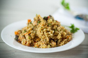 cooked bulgur with vegetables, carrots and dried mushrooms in a plate .