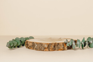 Wooden background with eucalyptus leaves for product presentation, beige tone. Aesthetic minimal...