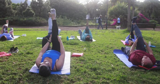 Multiracial senior people doing yoga exercises outdoor with city park in background - Healthy lifestyle and joyful elderly lifestyle concept