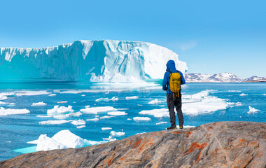 Environmental Concept - A Man Hiker looking at melting glacier - Melting of a iceberg and pouring...
