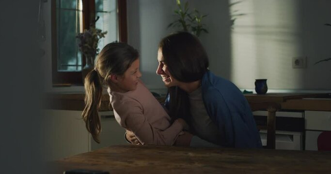 Authentic Shot of Mother Tickeling and Playing with her Daughter Then Hugging in The Kitchen at Home. Bonding Emotional Moment Expressing Motherly Love Between a Woman and Her Little Girl
