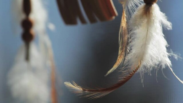 Close up shot of dreamcatcher feathers in front of window screen