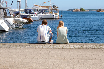 Eine junge Frau und eine junger Mann sitzen im Yachthafen von Kristiansand im südlichen Norwegen...