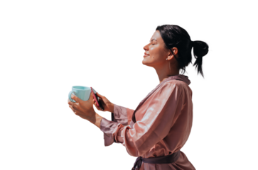 Relaxed young. Brunette hispanic woman in silk robe standing with cup of coffee eyes closed enjoying sun rays against transparent background. Tanned pretty caucasian girl on vacation at hotel.