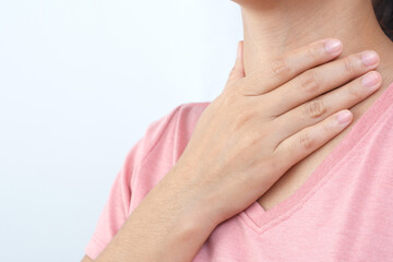 sore throat pain. Closeup of young woman sick holding her inflamed throat using hands to touch the ill neck in blue shirt on gray background. Medical and healthcare concept. Focus red on to show pain.