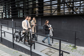 Group of business people walking outside in front of office buildings. Successful colleagues talking about new project promotion of their work and business ideas and solutions