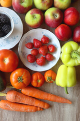 Berries in vintage porcelain dishes, other healthy fruit and vegetable on wooden table. Top view.