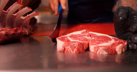 Chef making a heart shape form raw fresh beef meat ribeye. Juicy fresh meat steak on board with different meat goods around.