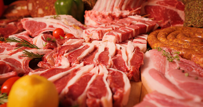 Meat products on display for sale on butchers table. Layout of various sausages and raw meat chunks. Handmade meat goods concept. - Powered by Adobe