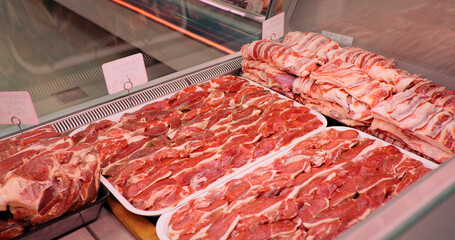 Raw lamb loin meat on metal trays ready to be sold in market. Shop front window filled with good...