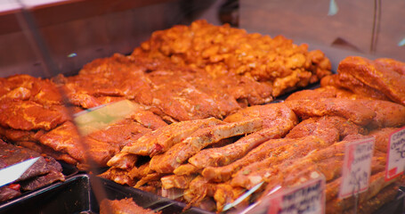 Large range of seasoned meat with spices and herbs in showcase in shop. Close up meat prepared for barbecue.