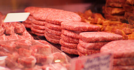 Beef burgers and other meat preps ready to be sold. Food industry. Raw minced meat beef burger cutlets in a window shop.