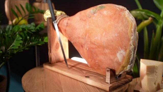 Typical cured Italian ham on special wood stand and knife for slicing, fat jamon leg for antipasto, Italian or Spanish delicacy