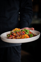 chef hand hold plate whith Stewed pork slice with noodles and vegetables