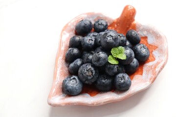 Fresh blueberries with mint leaves. The fruits are actual berries with many tiny seeds and are deep...