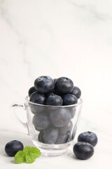 Fresh blueberries with mint leaves. The fruits are actual berries with many tiny seeds and are deep indigo to black color when ripe. Copy space.