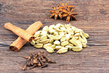 Star anise, cinnamon and cardamom with cloves on a wooden background.