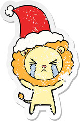 distressed sticker cartoon of a crying lion wearing santa hat