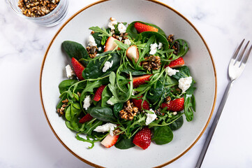 Healthy Salad made from Green Salad Leaves, Rocket Salad, Slices of Fresh Strawberries, pieces of Feta Cheese and Different Seeds.