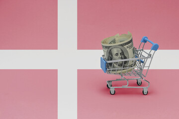 Metal shopping basket with dollar money banknote on the national flag of denmark background. consumer basket concept. 3d illustration