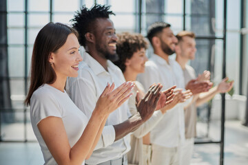 Group of businesspeople sitting in a line and applauding.