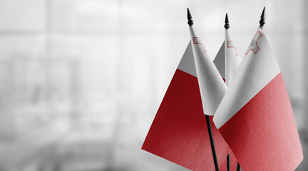 Small flags of the Malta on an abstract blurry background