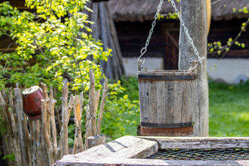 Wooden bucket from a well in the background a country cottage