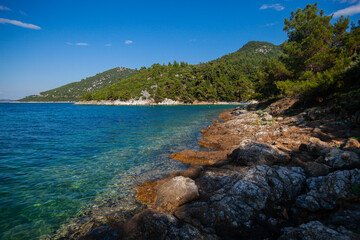 Tranquil beach scene with rocks, clear blue sky and serene sea water. Beautiful reminder of natures beauty on a sunny day. Enjoy a tranquil summer day at this idyllic shoreline.	