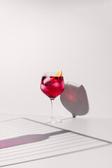 Refrescante gin y tónica rosa adornado con naranja sobre un fondo con sombras
