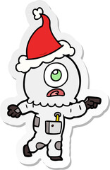 sticker cartoon of a cyclops alien spaceman pointing wearing santa hat