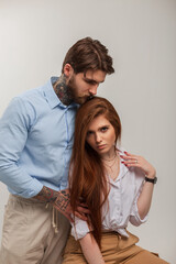 Fashionable beautiful couple. Stylish brutal handsome man with a tattoo and a beard and a beautiful red-haired model girl in a white shirt