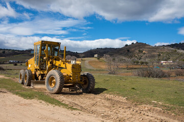 Obraz premium A tractor is used to remove dirt from a dirt road.