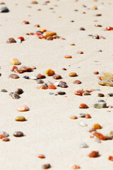 Sea stones amber yellow colored on natural fine beige  sand shore background, copy space. Natural colorful pebbles, monochrome Minimal nature summer landscape, beautiful beach, selective focus