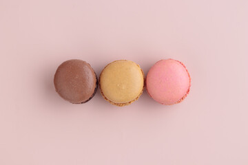 Three pastel colored macaroons on pink background, colorful french cookies pattern. Gift for 8 March, International Women's Day, Valentine Day