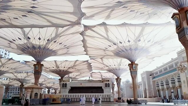 Medina, Saudi Arabia, 2022 - Umbrella construction on the square of Al-Masjid An-Nabawi or Prophet Muhammed Mosque are protecting people from sun at the daytime and works as lights at night