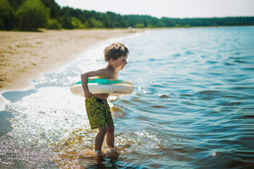 boy running into water with splashes and laughter. Vacation on sea side. Happy childhood.