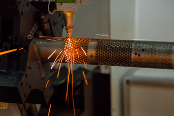 CNC laser cutting machine working with cylindrical metal workpiece with many sparks at factory,...
