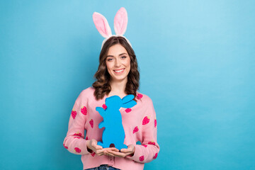 Photo of cheerful cute lady dressed pink cardigan easter hairband holding arms rabbit empty space isolated blue color background