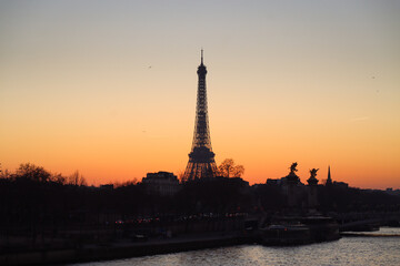 Fototapeta na wymiar A silhouette of Eiffel tower at sunset with Seine river surround with building and urban scenic of Paris with orange sky in the evening 