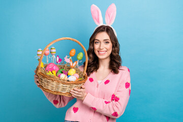 Photo of positive cute lady dressed pink cardigan rising easter snacks basket isolated blue color background