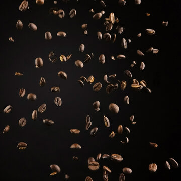 Aromatic coffee grains dropping against brown background
