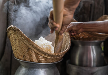Hands of a person in the kitchen cook sticky rice with pot and rice steamer, traditional original...