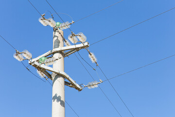 Concrete electricity pylon against a blue background with copper