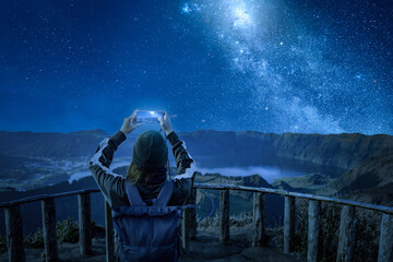 Woman with a smartphone under a starry night sky