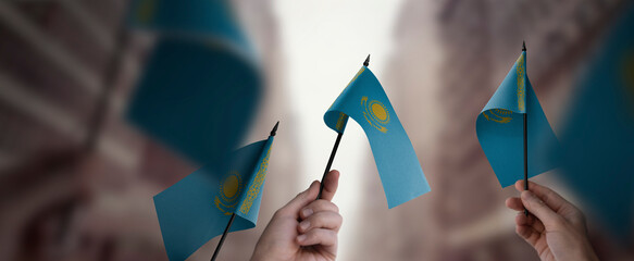 A group of people holding small flags of the Kazakhstan in their hands - obrazy, fototapety, plakaty