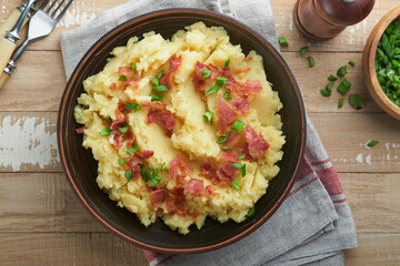 Mashed potatoes. Bacon mashed potatoes with green onion, pepper and cheddar cheese in bowl on old wooden backgrounds. Delicious creamy mashed potatoes. Top view.
